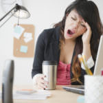Pacific Islander businesswoman yawning at desk