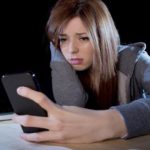 worried teenager using mobile phone and computer  cyber bullying victim
