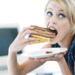 Close-up-of-a-woman-eating-a-large-piece-of-cake-768×511