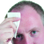 A businessman wiping his sweat from his forehead
