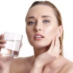 beautiful young beautiful woman drinking fresh water on white