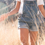 Mid section of young hiking couple touching long grass while hiking in valley, Las Palmas, Canary Islands, Spain