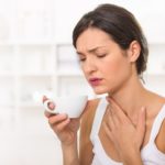 Young woman with a sore throat drinking tea