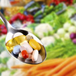 spoon with pills, dietary supplements on vegetables background