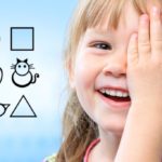 Close up face shot of little girl closing one eye with hand. Childish symbols in background as vision test chart.