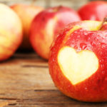 33642425 – red apple with heart on wooden table, close-up