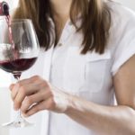 Germany, Saxony, Mid adult woman pouring wine into glass, close up