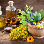Essential oil, mortar with fresh herbs and bath salt on wooden b