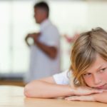 Sad looking boy with fighting parents behind him