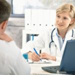 Doctor talking to patient in office, taking notes, smiling.?