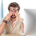 Young man with eyes pain touching his eyes