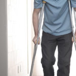 Young man using crutches in hospital.