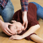 Man Placing Woman In Recovery Position After Accident