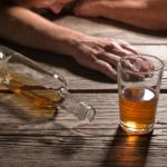 alcoholic-slumped-next-to-glass-of-alcohol