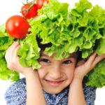 Kid with salad and tomato hat on his head, fake hair made of veg