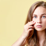 Young redhead teenager with self issues looking into mirror. Girl with low self esteem checking her skin in a mirror.