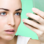 young woman looking into a mirror to check her make up
