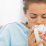 Ill young woman drinking hot beverage