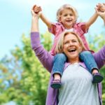 Portrait of a happy grandmother holding her grandchild on her shoulders