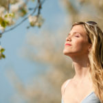 Spring – Young woman under blossom tree enjoy sun