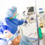 Anesthesiologist checking monitors while sedating patient for surgery in hospital