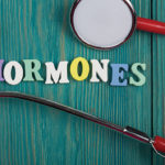 Text “Hormones” of colored wooden letters, stethoscope and pills