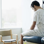 Male patient in gown waiting on exam table