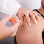 Male with lip piercing gets a shot from a female doctor