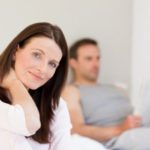 Lovely woman looking at the camera while her husband is sleeping