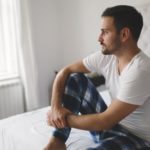 man-sitting-on-a-bed-looking-contemplative-suffering-from-erectile-dysfunction-or-ed