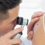 Dermatologist checking mole on woman