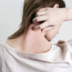 Close up view of woman scratching her neck.