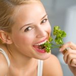Young happy smiling woman eating at kitchen