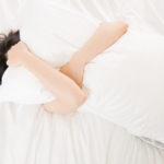 beautiful asian woman feel unwell painful and holding pillow
