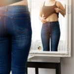 woman checking her body in front of mirror