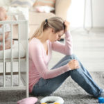 Depressed young woman with cute baby at home