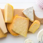 Different kinds of cheeses on white wooden table. Top view.