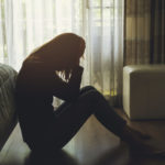 depressed woman sitting in the dark bedroom