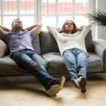 Young couple relaxing together on sofa enjoying nap breathing air