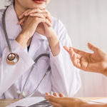 female doctor listening to depressed patient talking at hospital