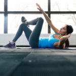 Young woman lying on the yoga mat and doing exercise