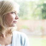 Sad Mature Woman Suffering From Agoraphobia Looking Out Of Windo
