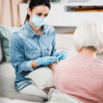 Female doctor sitting on couch with old woman