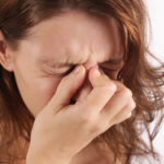 Studio shot of a young woman suffering from symptoms of sinus Infection (Sinusitis)