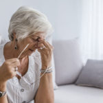 Elderly woman suffering from headache at home