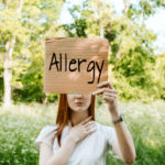 Young,Redhead,Woman,Covers,Her,Face,With,Sign,Text,Allergy.