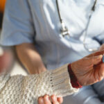 Mature woman sitting near doctor and holding thermometer