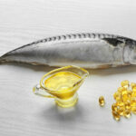 Fish oil pills and fresh fish on light background