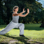 Side portrait of a woman doing tai chi exercise in natural environment.