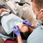 Dentist examining woman teeth with diagnostic microscope.